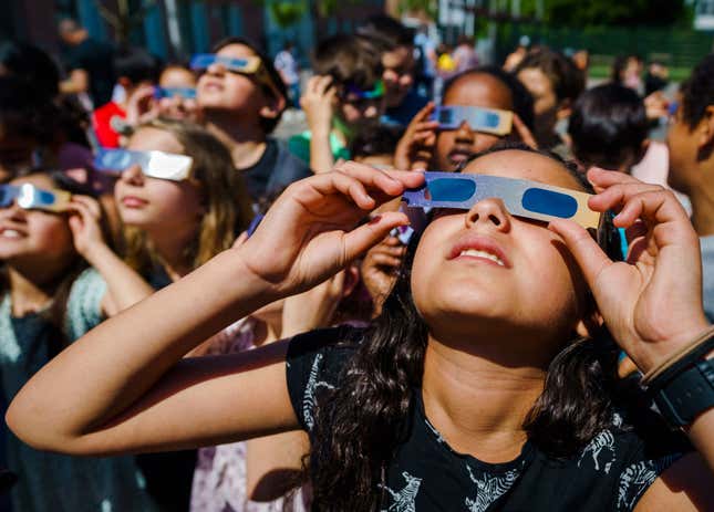 Children watching a solar eclipse with safety glasses