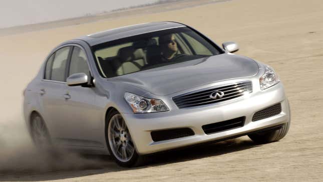 A photo of a silver Infiniti sedan driving on sand. 