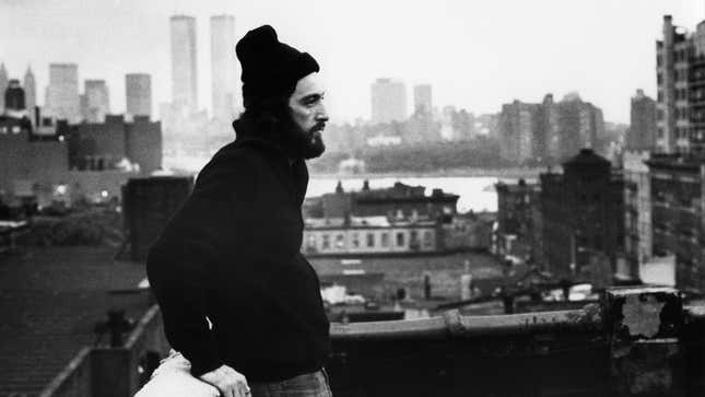 Al Pacino wearing a sweatshirt and a beanie on a rooftop overlooking NYC.