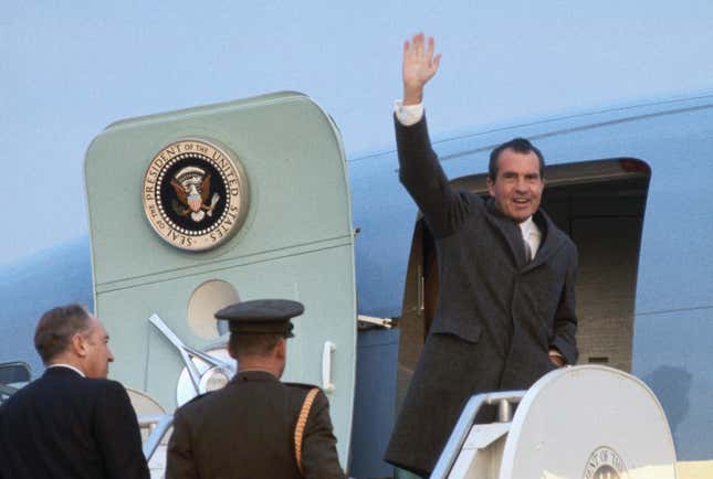 President Richard Nixon waves as he boards Air Force One for Key Biscayne, FL. He is accompanied by Secretary of State William Rogers and an military aide.