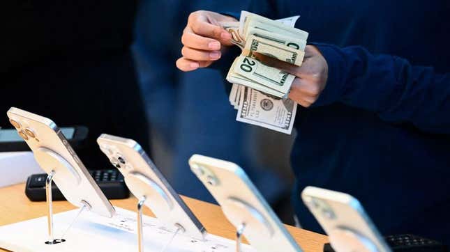 A person counts money in front of an iPhone display.