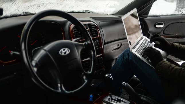 A photo of someone using a laptop to hack a car. 