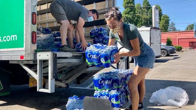 Volunteers and Multnomah County employees unload cases of water to supply a 24-hour cooling center set up in Portland, Oregon on Wednesday, Aug. 11, 2021.