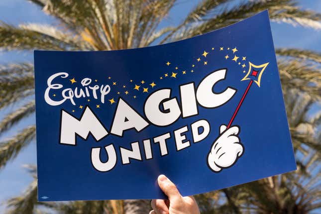 A Disneyland employee holding a sign for the Magic United workers group.