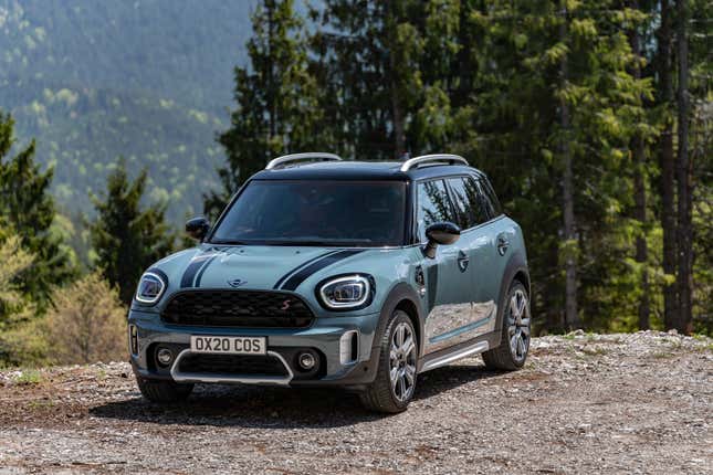 A teal and black Mini Countryman S parked on gravel in the woods
