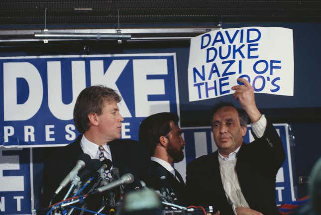  Ein Demonstrant hält ein Schild mit der Aufschrift „David Duke, der Nazi der 90er“ hoch und unterbricht damit David Dukes Rede während einer Wahlkampfkundgebung. 