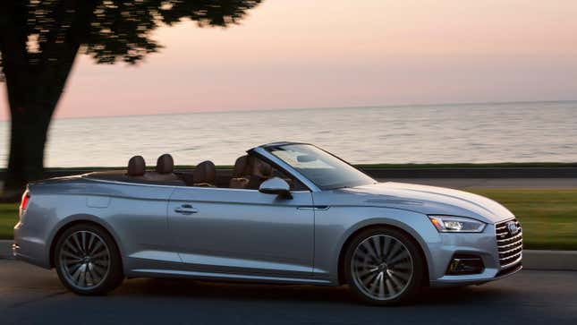 A silver A5 cabriolet driving in front of a body of water