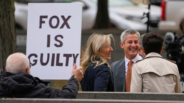 A protester holds a sign near representatives of Fox News outside the justice center for the Dominion Voting Systems’ defamation lawsuit against Fox News, Tuesday, April 18, 2023, in Wilmington, Del.