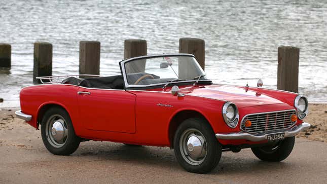 A red Honda S600 convertible on a beach 