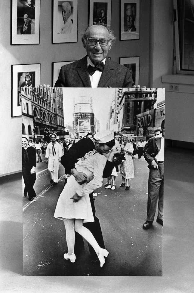 German-American photographer and photojournalist Alfred Eisenstaedt  poses at the opening on May 5, 1986, of an exhibition of his famous  pictures taken for Life magazine at the Kultur Kontor der Hamburger  Hanse Vier, in Hamburg, Germany, with one of his best-known photographs  taken during the celebrations of V-J Day in Times Square, New York on  August 1945. 