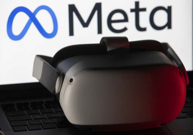 The logo of “Meta” is displayed on computer screen behind the VR headset.