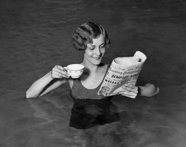 A young woman takes her cup of morning tea and newspaper into the swimming pool. (Photo by © Hulton-Deutsch Collection/CORBIS/Corbis via Getty Images)