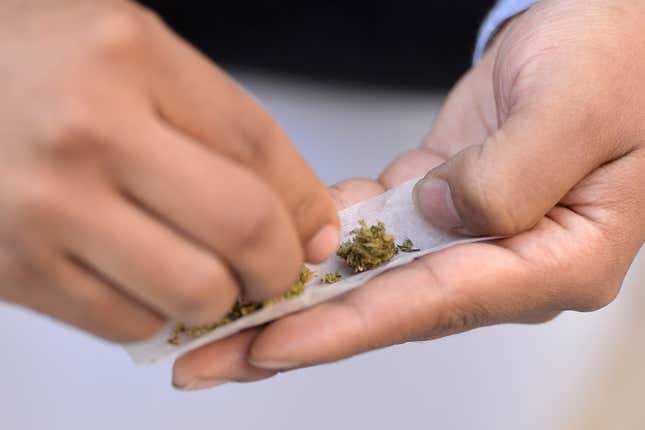 A man sitting outside of ‘Weed World Candies’ prepares to smoke cannabis, after Gov. Andrew Cuomo signed into law a bill to legalize recreational marijuana, New York, NY, April 7, 2021.