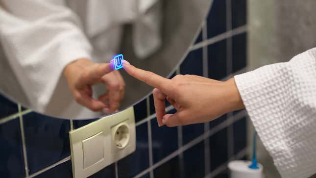 woman wearing a robe pressing button for turning on light and heating mirror in bathroom closeup 