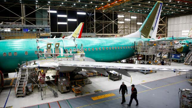 Two workers walk under the wing of a 737 Max aircraft at the Boeing factory in Renton, Washington, U.S., March 27, 2019.
