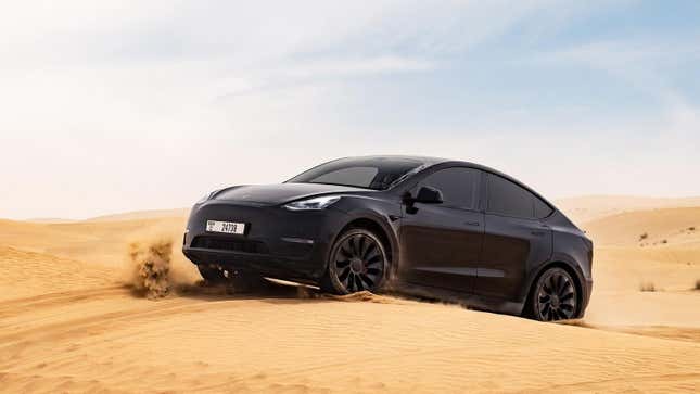 A black Model Y driving on sand dunes