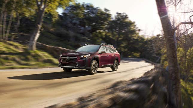 A burgundy Subaru Outback driving on a tree-lined road