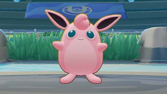 Wigglytuff, a round, pink Pokémon, smiles in the middle of a Pokémon Unite arena.