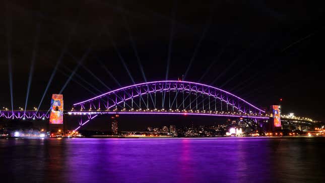 A photo of the Sydeny Harbour Bridge illuminated with purple lights. 