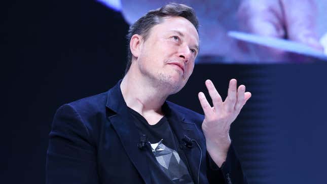 A photo of Elon Musk with his hands in the air. 