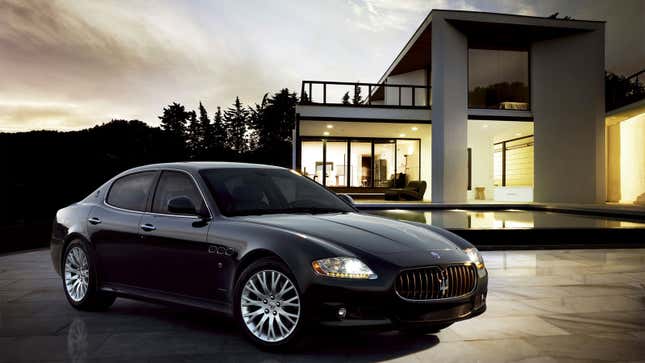 A photo of a black Maserati Quattroporte in front of a large house. 