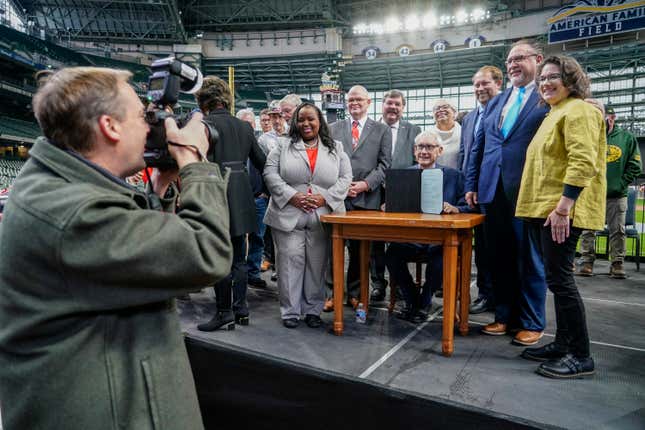 Photographer Joe Koshollek takes a picture of Wisconsin Gov. Tony Evers after Ecvers signed Assembly Bill 438 and Assembly Bill 439 at American Family Field Tuesday, Dec. 5, 2023, in Milwaukee. The bills use public funds to help the Milwaukee Brewers repair their stadium over the next three decades. (AP Photo/Morry Gash)