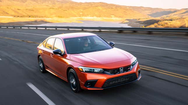 A photo of an orange Honda Civic SI sedan driving on a highway. 