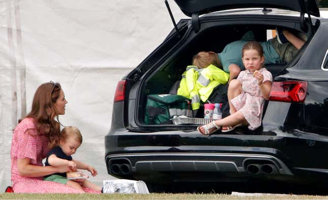 A mother and her three kids having a picnic out of the back of their station wagon