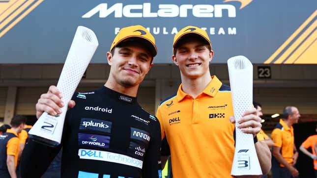 Una foto de los pilotos de McLaren Lando Norris y Oscar Piastri sosteniendo trofeos. 