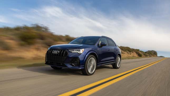 A dark blue Audi Q3 driving down a rural road