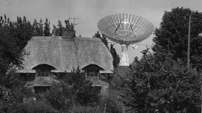 A giant dish aerial situated near a thatched cottage in Oakhanger, Hampshire.