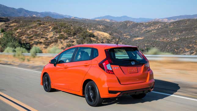 An orange Honda Fit on a mountain road