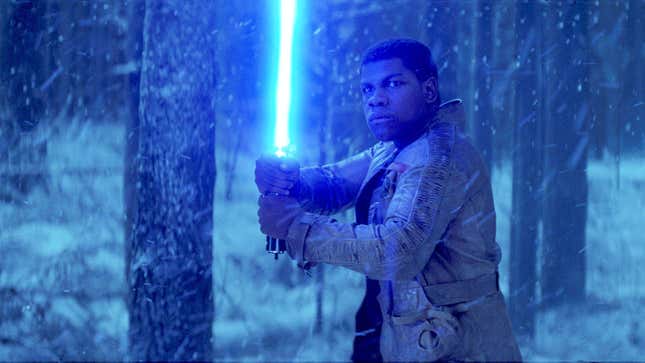 John Boyega as Finn, holding a blue lightsaber in a snowy forest. 