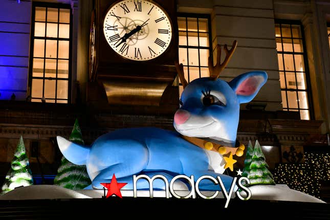 A blue reindeer figure sits on top of a Macy's department store sign.