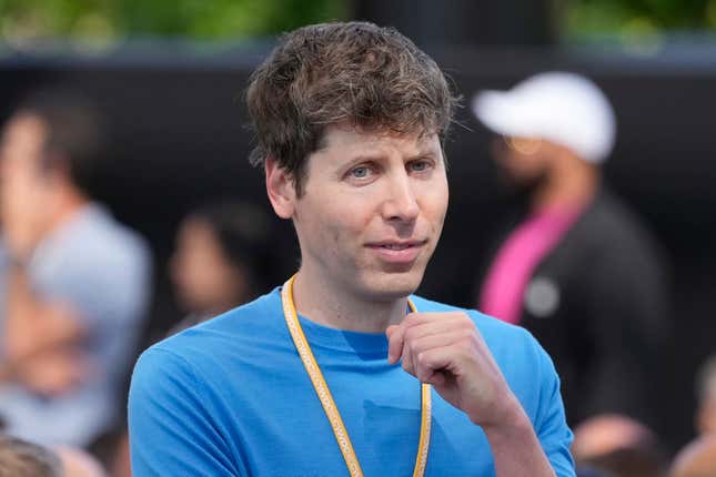 Sam Altman con una camisa azul de manga larga y un cordón naranja y sosteniendo un puño