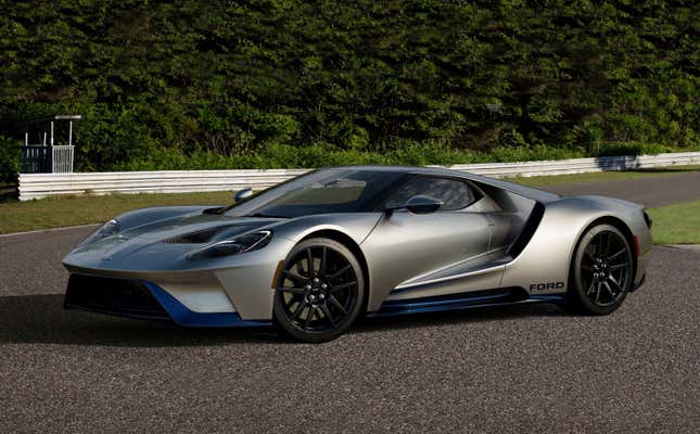 A silver and blue Ford GT sits parked on a race track.