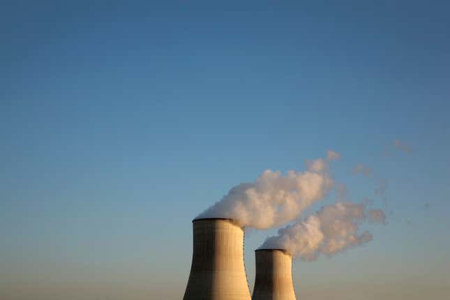 nuclear reactors with smoke coming out the top against a blue sky