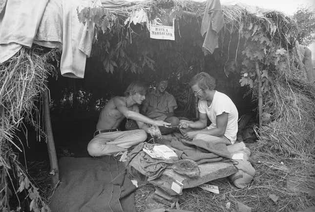 FILE - Music fans seek shelter is a grass hut at the Woodstock Music and Art Festival in Bethel, N.Y., Aug. 17, 1969. The sign above reads &quot;Have a Marijuana.&quot; (AP Photo, File)