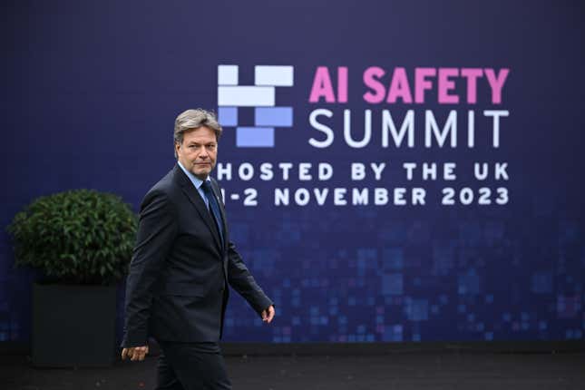 Robert wearing a black suit walking in front of a backdrop with the AI Safety Summit logo