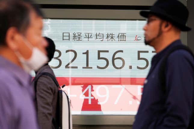 People walk in front of an electronic stock board showing Japan&#39;s Nikkei 225 index at a securities firm Tuesday, Oct. 17, 2023, in Tokyo. (AP Photo/Eugene Hoshiko)