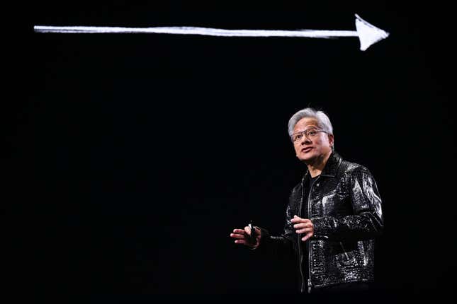 Jensen Huang speaking while wearing a black leather jacket, a black backdrop behind him has a white arrow on it