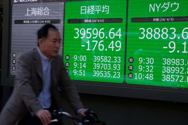 A cyclist moves past an electronic stock board showing Japan&#39;s Nikkei 225 index, left, at a securities firm Wednesday, April 10, 2024 in Tokyo. (AP Photo/Shuji Kajiyama)