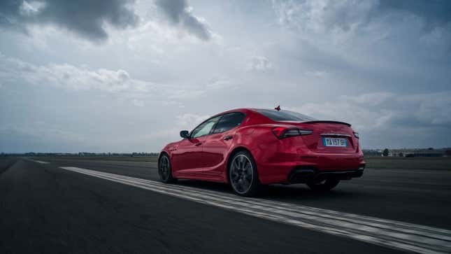 A photo of a red Maserati Ghibli on a race track. 