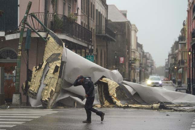 A man passes by a section of roof that was blown off of a building in the French Quarter by Hurricane Ida winds, Sunday, Aug. 29, 2021, in New Orleans. 