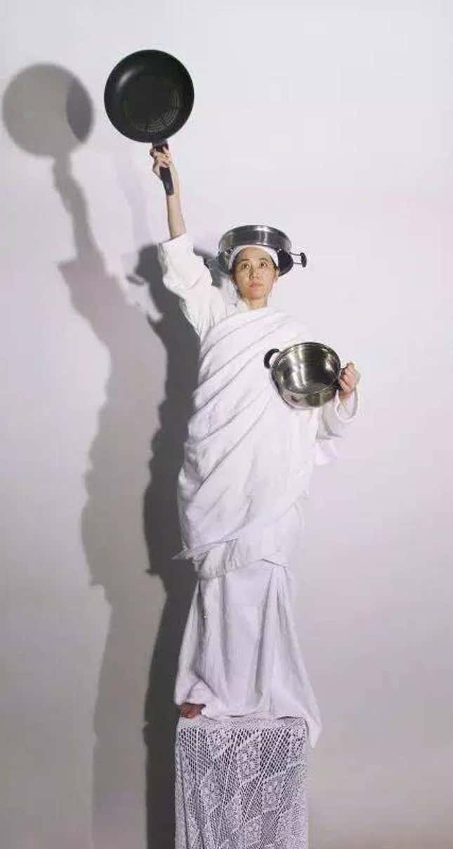 A woman with pots, posting like the Statue of Liberty, by Lu Feifei.