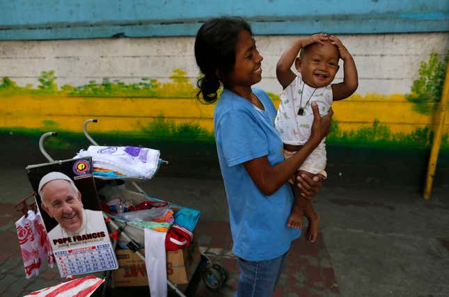 Filipina Flor, 20, holds her son Vincent as she tries to sell souvenirs along the Pope Francis motorcade route in Manila, Philippines, Thursday, Jan. 15, 2015.