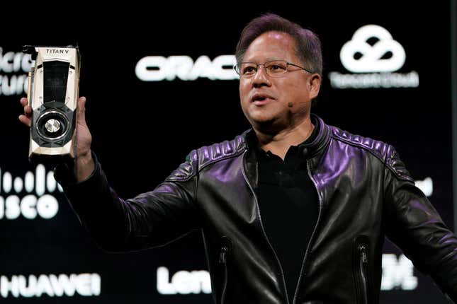 Jensen Huang holding up the Titan V chip. He's wearing a black leather jacket.