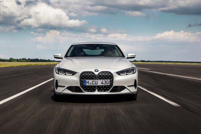 A white 2021 BMW 430i driving directly at the camera, showcasing its wretched bucktooth grille