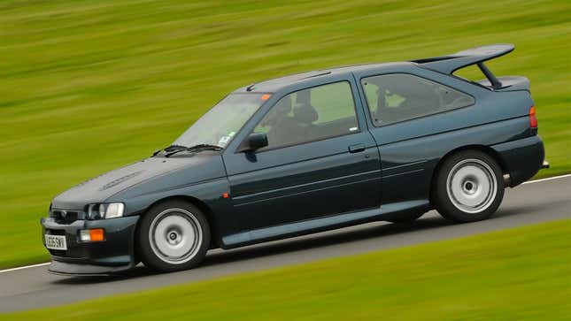 A green Ford Escort Cosworth on a race track. 