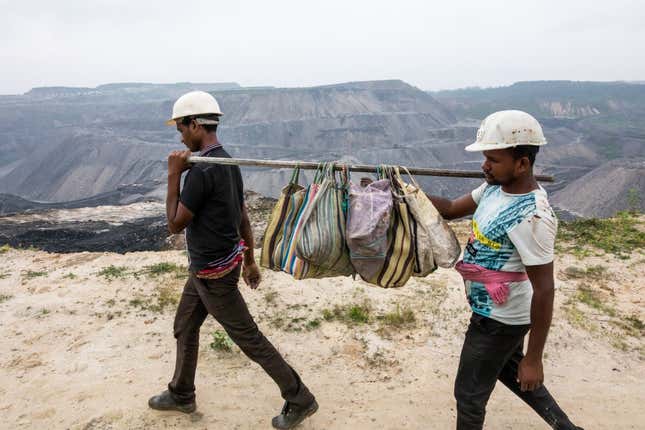 Workers laying a power line carry the team’s lunch boxes at the Dipka Extension mine near Hardi Bazar in Korba. Coal mines have to run electric pumps to drain out any water collected at the bottom of the open pits.